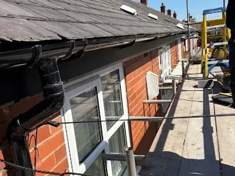 New black guttering and downpipe fitted to a red brick house
