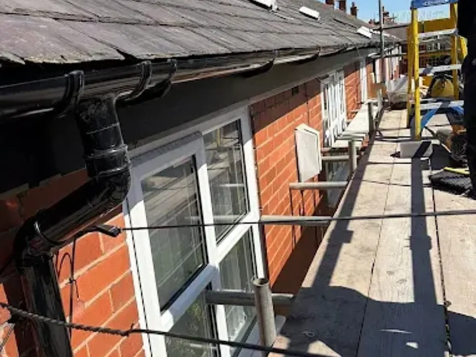 New black guttering and downpipe on a red brick house