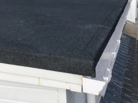 Newly finished flat roof with clean white fascia and guttering