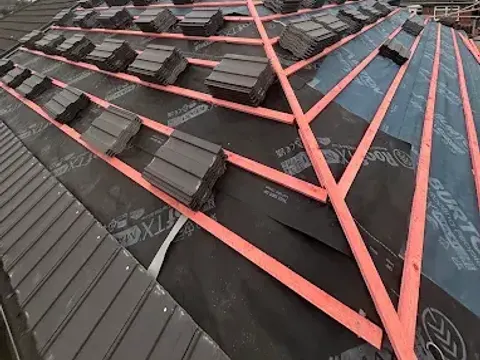 New roof mid-installation with fresh battens, underlay and roof tiles stacked ready to lay