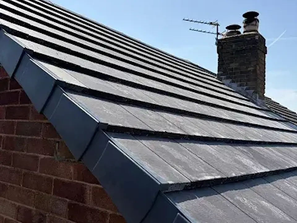 New grey tiled roof below a brick chimney with pots