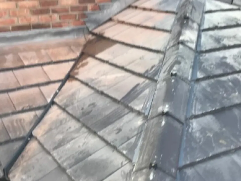 Slate roof valley with lead detail beside a brick chimney