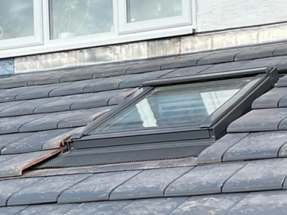 Velux roof window being fitted in a grey tiled roof